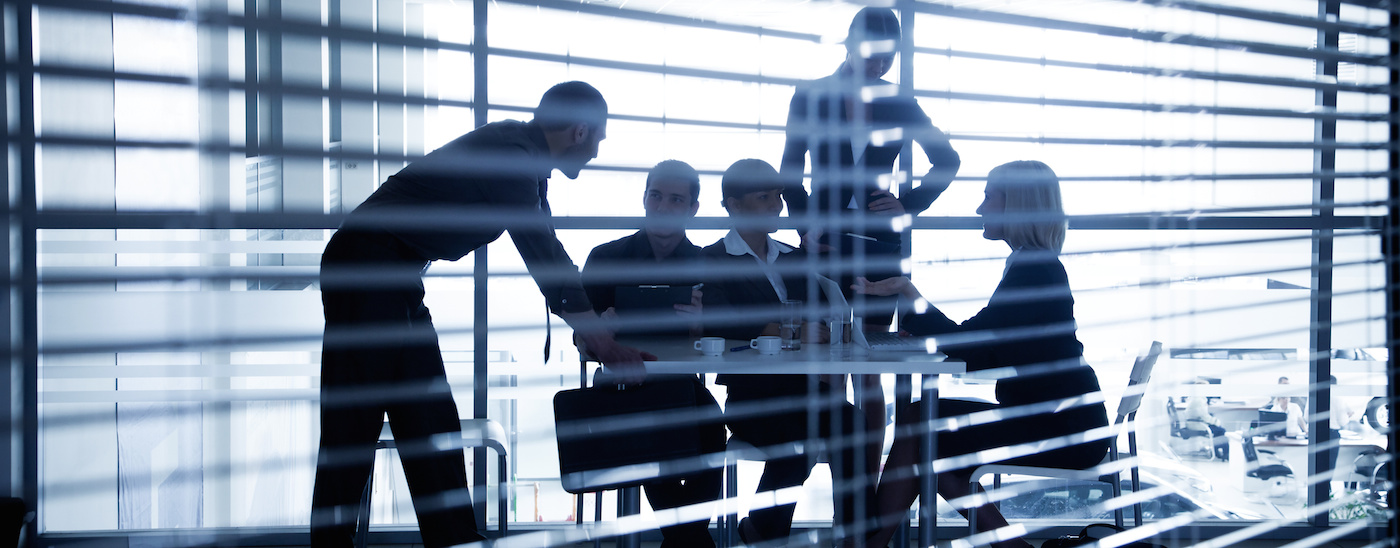 silhouettes of business people through the blinds